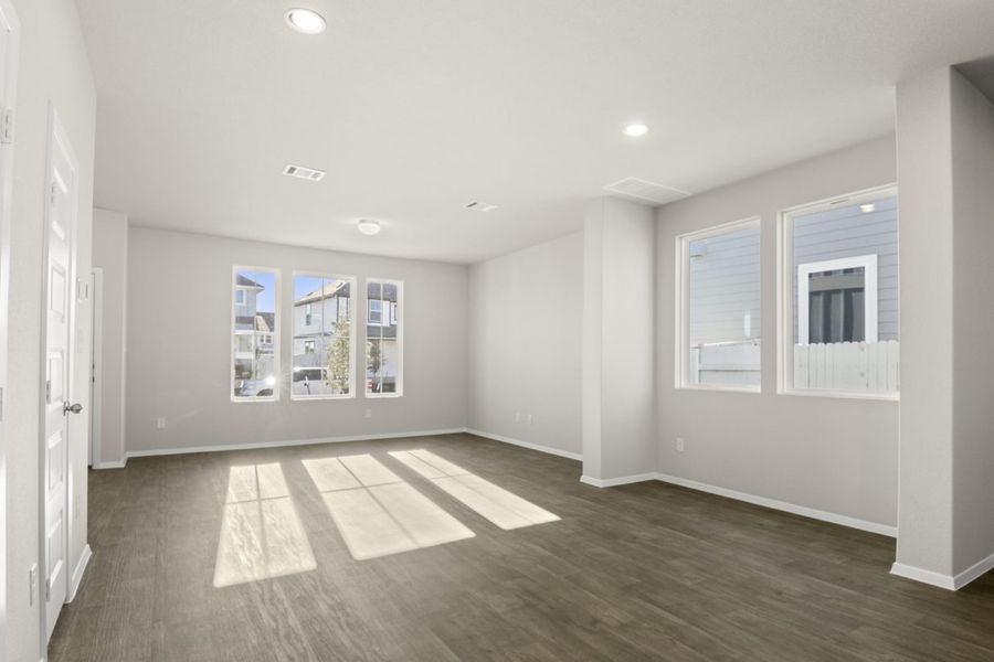 Image of a living and dining room with dark vinyl flooring, light grey walls, windows and white trim