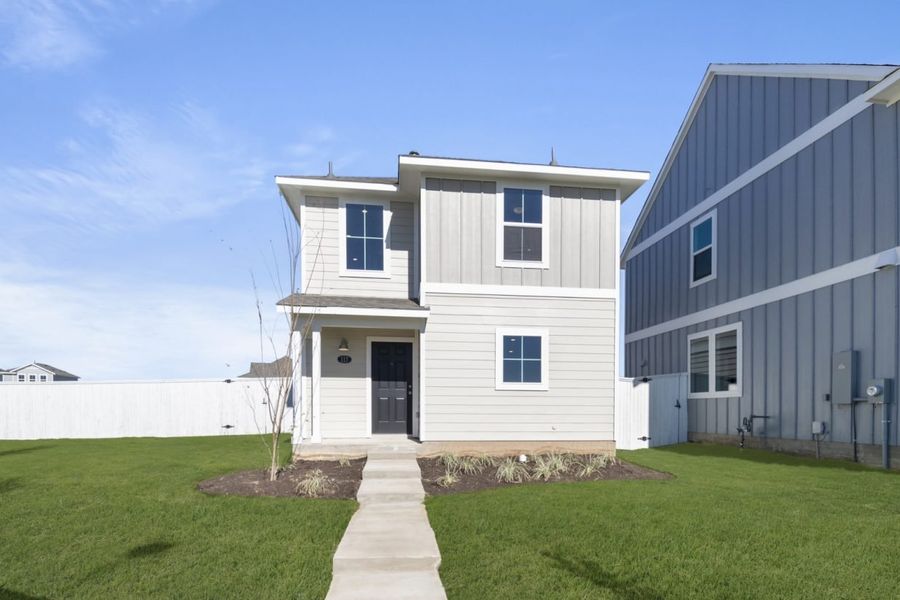 Image of a two story beige home exterior with windows, white trim, a brown door, a cement pathway, and a green grass front yard and a blue sky background