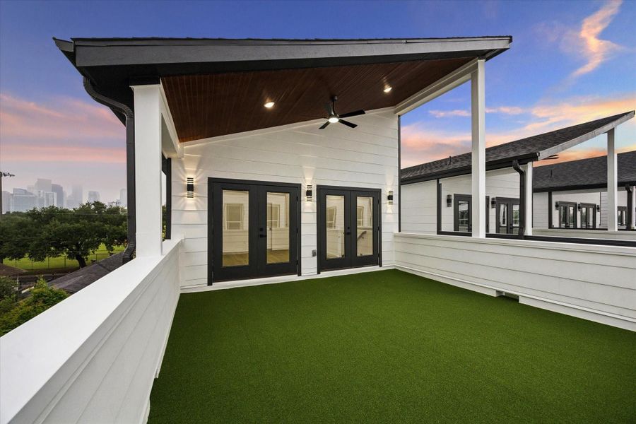 This photo showcases a spacious rooftop terrace with artificial grass, modern lighting, and ceiling fan. It features double doors leading inside and offers a view of the city skyline, perfect for outdoor relaxation or entertaining. This photo showcases a spacious rooftop terrace with artificial grass, modern lighting, and ceiling fan. It features double doors leading inside and offers a view of the city skyline, perfect for outdoor relaxation or entertaining.