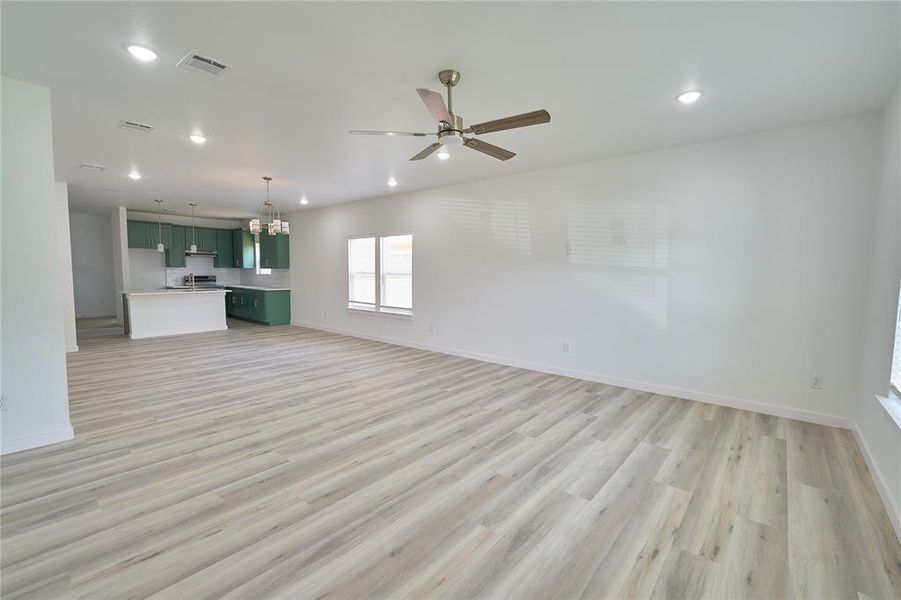 Expansive open-concept living area featuring light wood-finish flooring, recessed lighting, and a ceiling fan