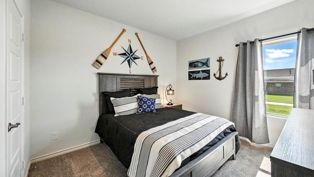 This bedroom features light grey walls and carpet, a window with grey curtains, and a textured headboard