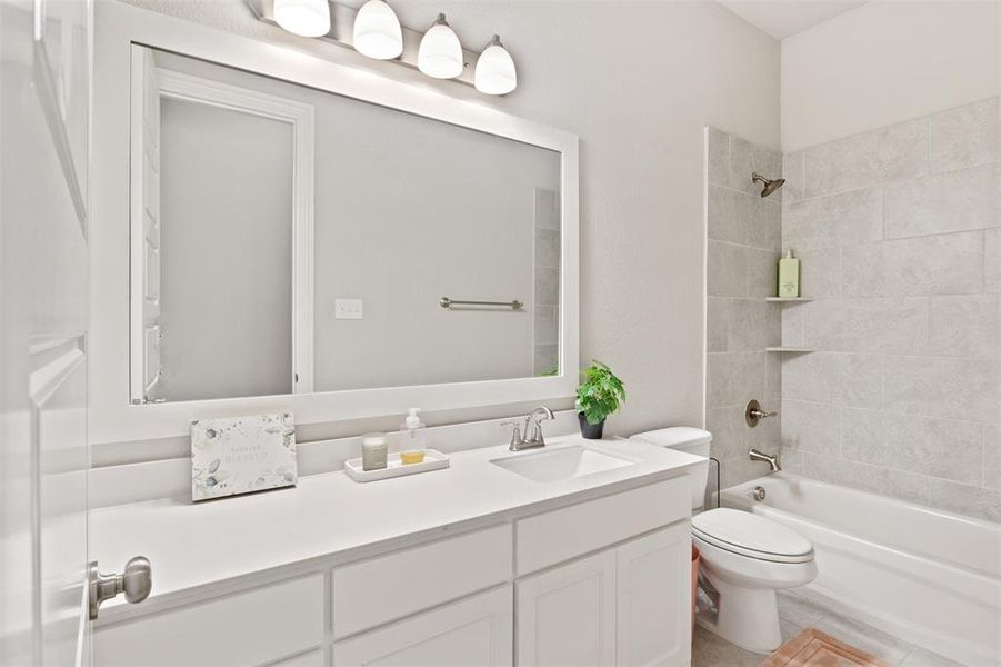 Full bathroom with vanity, tiled shower / bath combo, toilet, and tile patterned floors