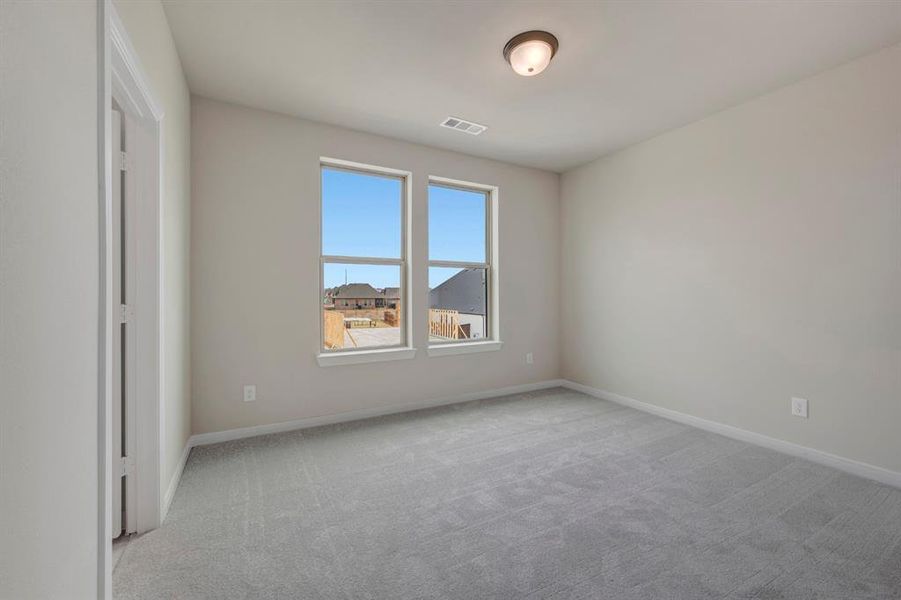 Empty room with light colored carpet and baseboards