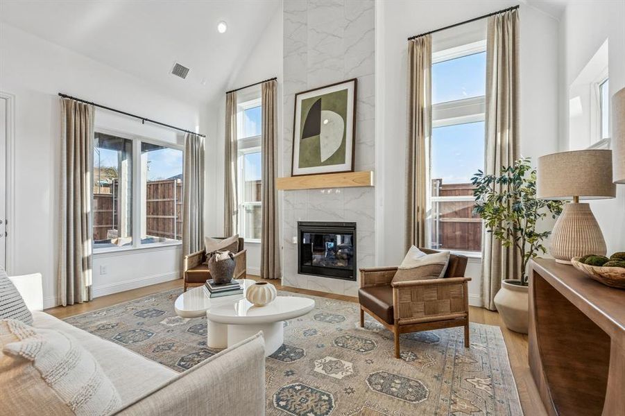Living area with light wood-type flooring, a high end fireplace, vaulted ceiling, plenty of natural light, and recessed lighting