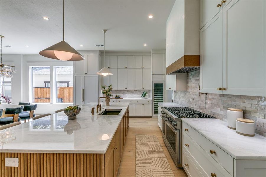 Kitchen featuring sink, premium range hood, backsplash, and a large island