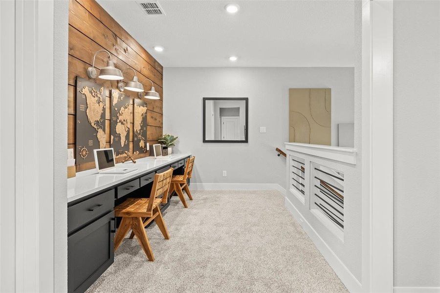 Office space with light colored carpet, recessed lighting, wood walls, and built in desk