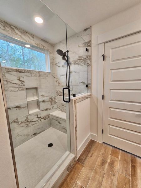Bathroom featuring a marble finish shower and wood finish floors
