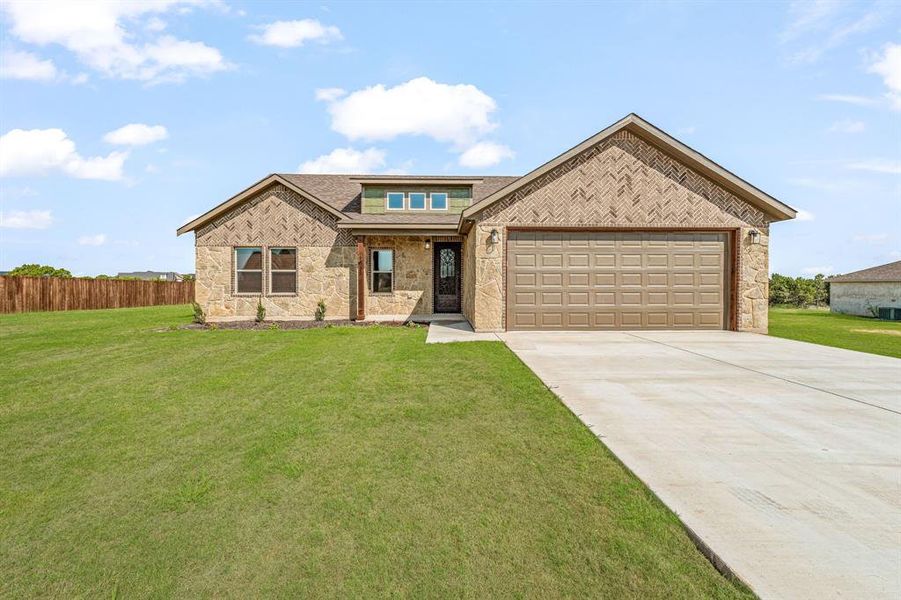 View of front facade featuring driveway, a shingled roof, covered porch, a garage, and brick siding