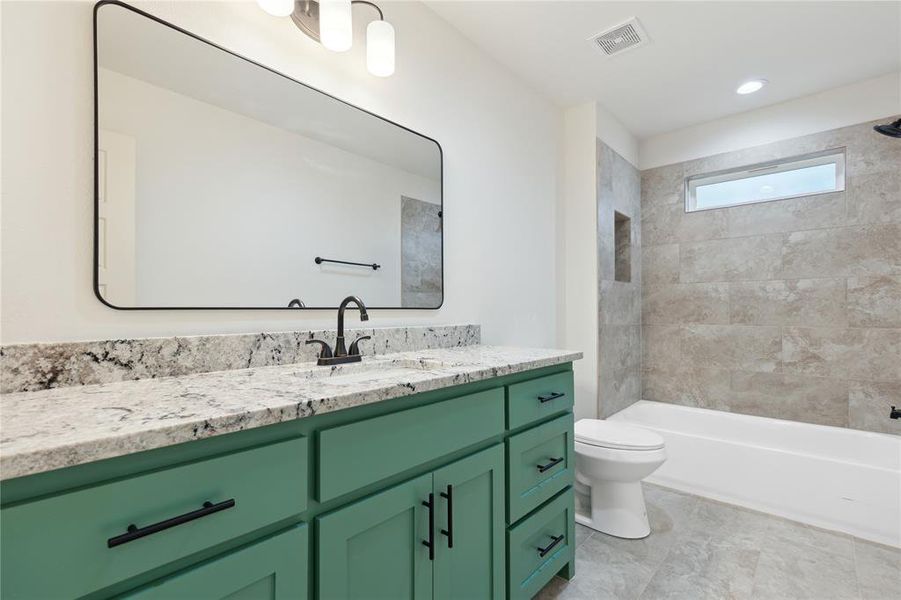 Full bathroom with tile flooring, tiled shower / bath, vanity, and toilet