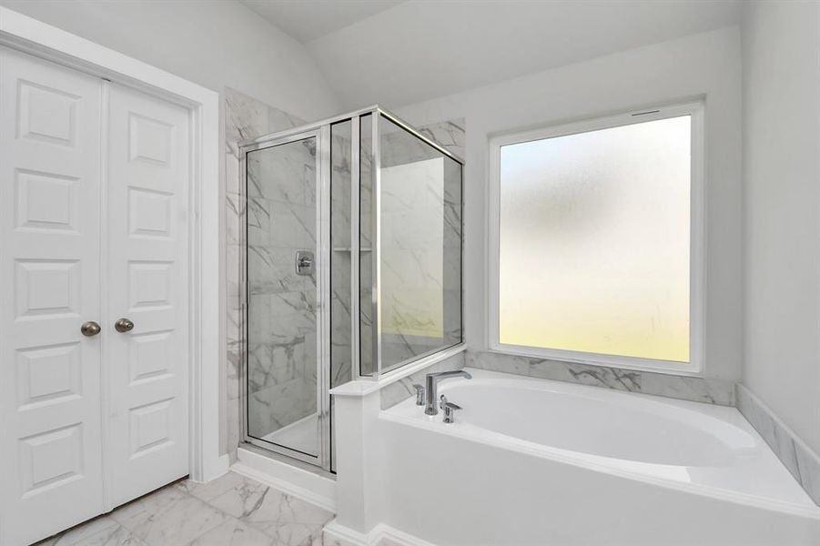 The primary en-suite has a soaking tub to give you that spa experience. The large privacy window allow lots of nature light in the space. Sample photo of completed home. As-built color and selections may vary.