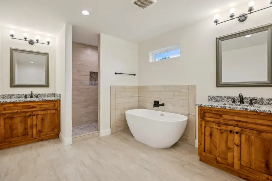 Full Primary bath with a tile shower, two vanities, a sink, and visible vents
