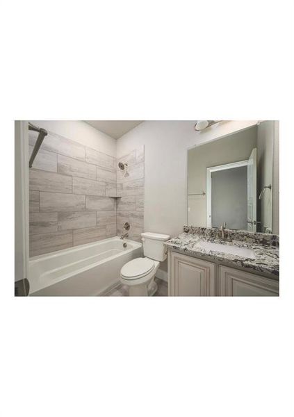 Full bathroom with vanity, tiled shower / bath combo, and toilet