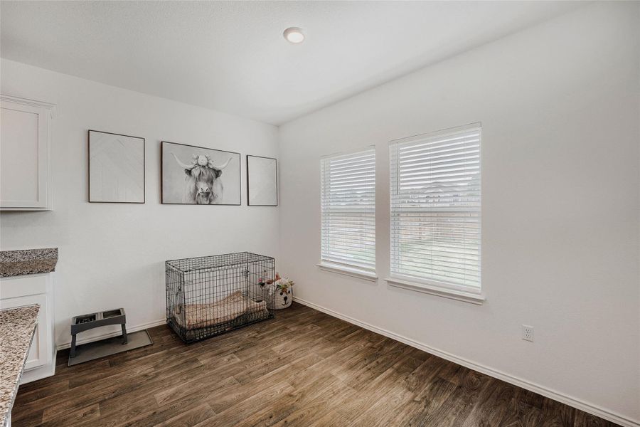 Interior room featuring two windows with horizontal blinds, wood-finish flooring, a white ceiling with recessed lighting, and white baseboards Interior room featuring two windows with horizontal blinds, wood-finish flooring, a white ceiling with recessed lighting, and white baseboards