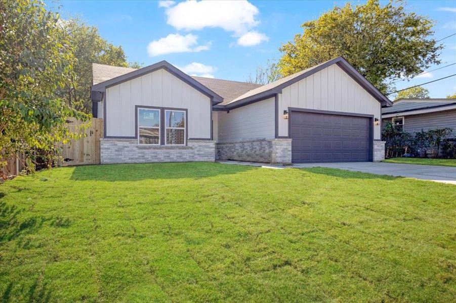 View of front of home with a garage and a front lawn