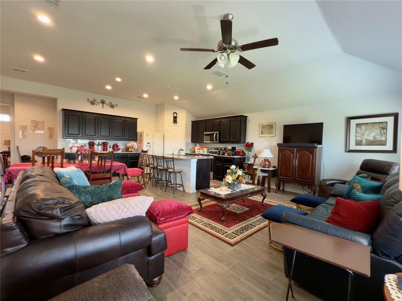 Living room featuring vaulted ceiling, recessed lighting, light wood-type flooring, and a ceiling fan Living room featuring vaulted ceiling, recessed lighting, light wood-type flooring, and a ceiling fan