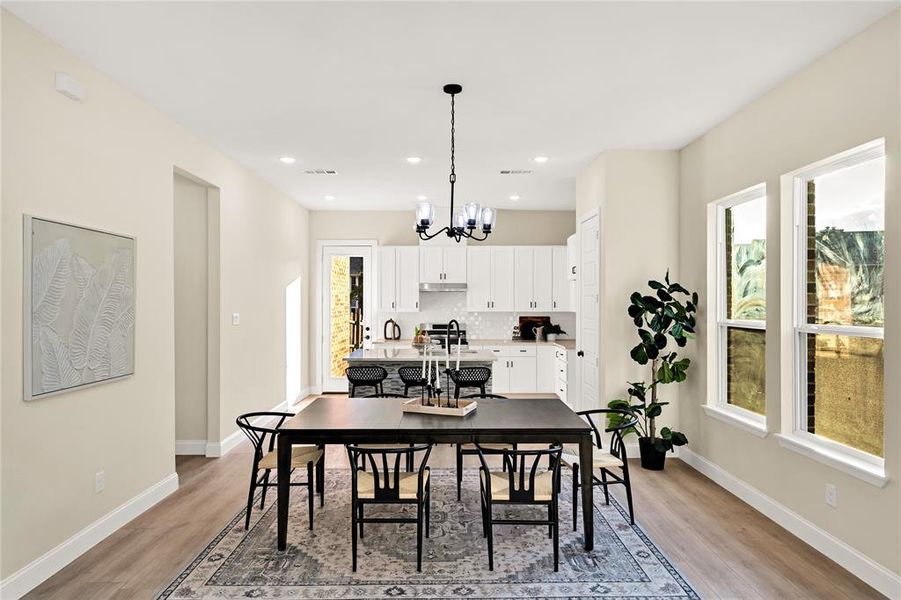 Dining area with light wood-type flooring, a wealth of natural light, and a notable chandelier