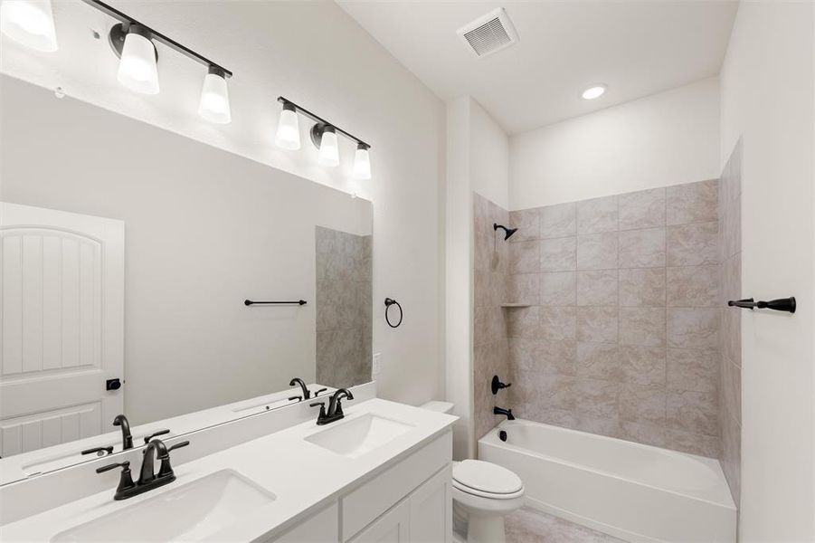 Bathroom with double vanity and bathtub / shower combination
