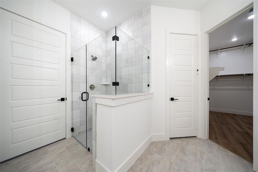 Full bath with a shower stall, a spacious closet, and recessed lighting
