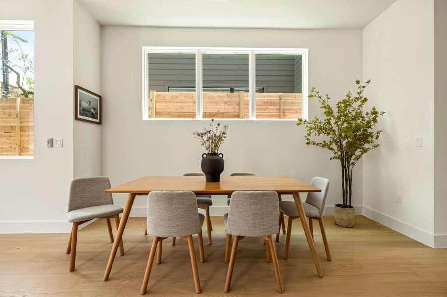Sun-filled dining space features bright, clear windows and warm hardwood flooring, perfect for gathering.