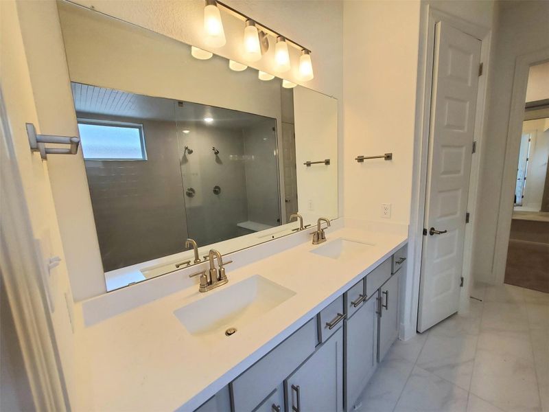 Bathroom with double vanity, marble finish floor, a stall shower, and a sink Bathroom with double vanity, marble finish floor, a stall shower, and a sink