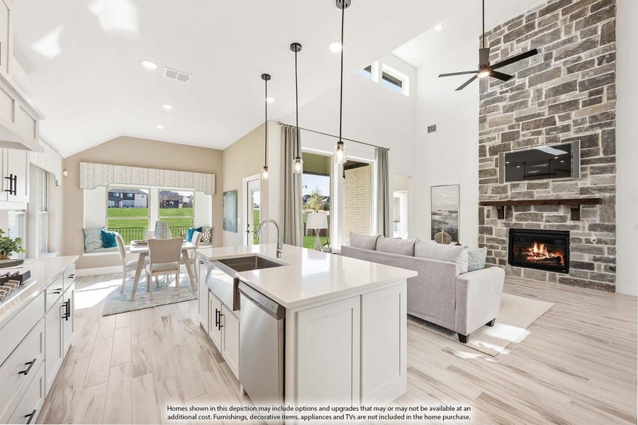 Open-concept kitchen and living area with white island, stone fireplace, vaulted ceiling, and dining space visible in background. Open-concept kitchen and living area with white island, stone fireplace, vaulted ceiling, and dining space visible in background.