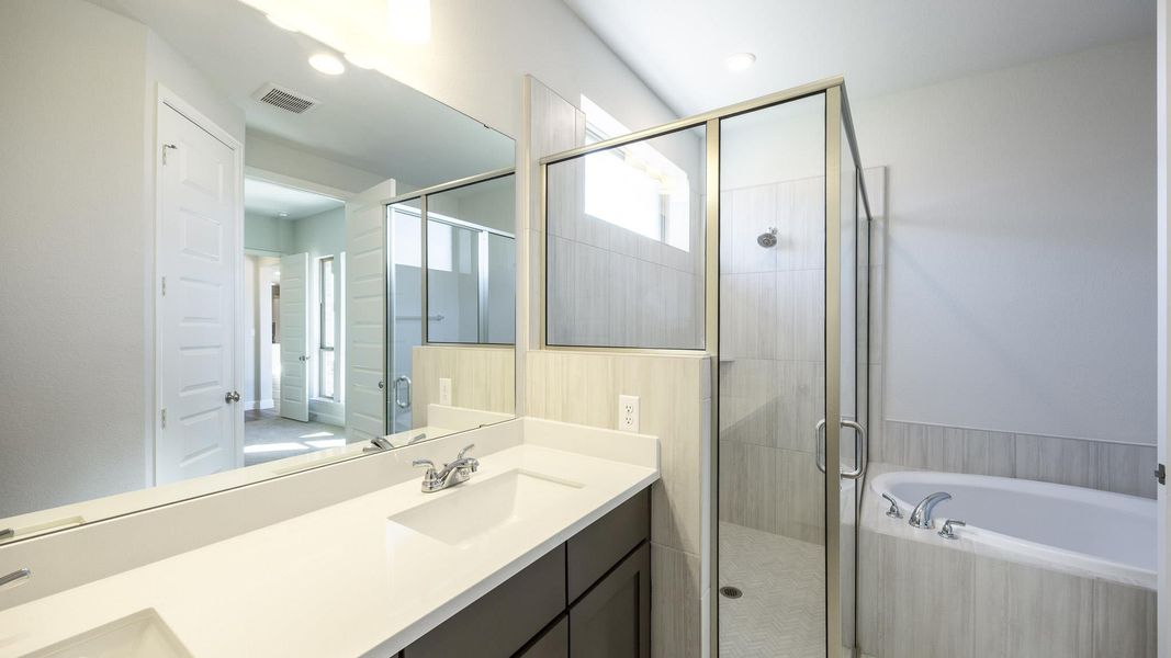 Bathroom featuring visible vents, double vanity, a stall shower, a sink, and a bath