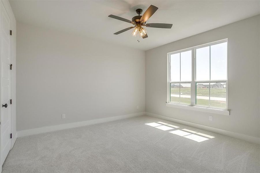 Carpeted spare room with baseboards and a ceiling fan Carpeted spare room with baseboards and a ceiling fan