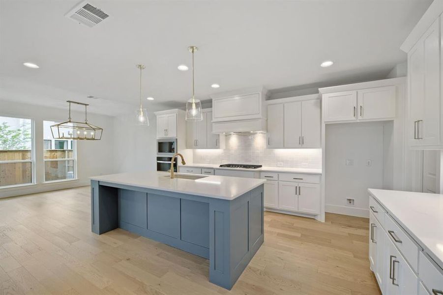 Modern kitchen featuring a blue-toned island with a white countertop and brass-finish faucet Modern kitchen featuring a blue-toned island with a white countertop and brass-finish faucet