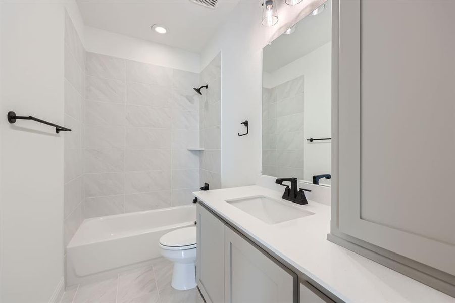 Full bathroom featuring tiled shower / bath combo, tile patterned flooring, toilet, and vanity