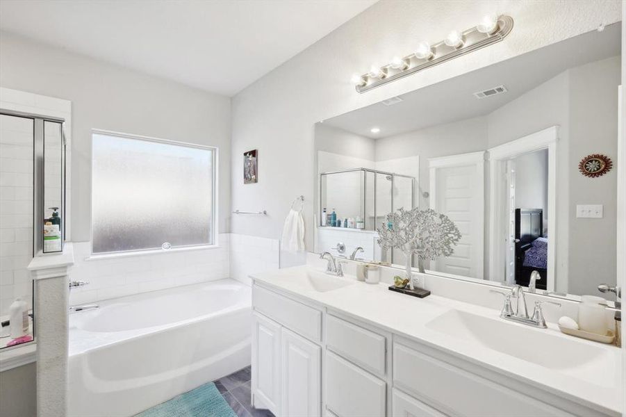 Bathroom featuring tile patterned flooring, shower with separate bathtub, and vanity