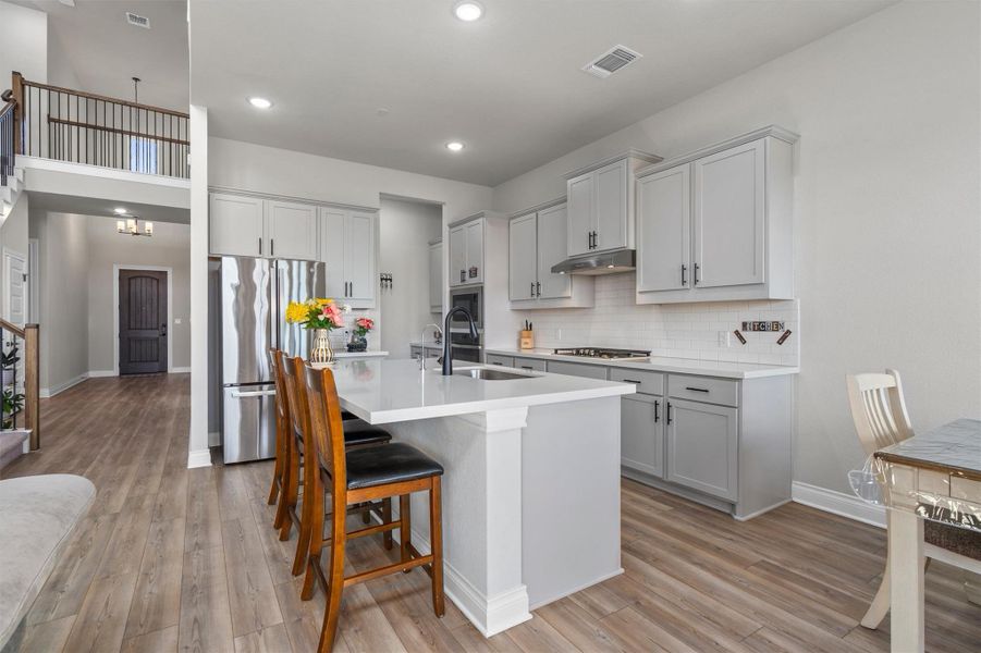 An open kitchen showcases sleek modern cabinetry alongside a central island and recessed lighting.