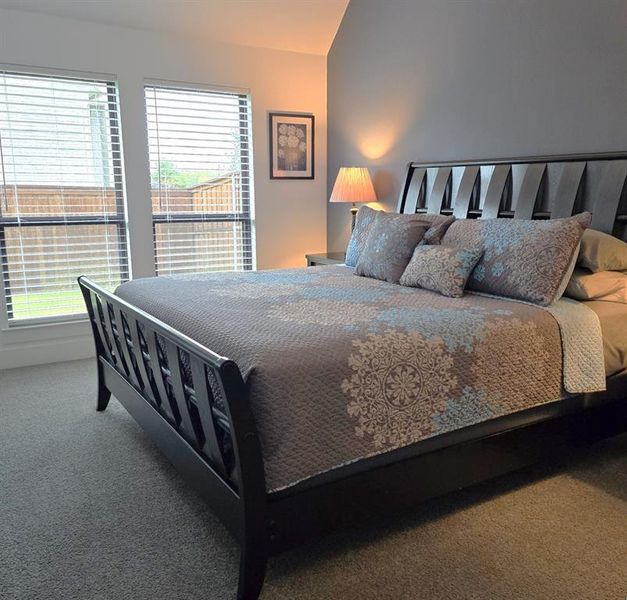 Bedroom featuring carpet flooring and vaulted ceiling Bedroom featuring carpet flooring and vaulted ceiling