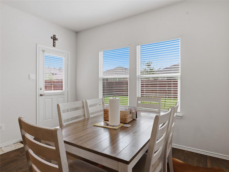 Natural light streams through large windows, illuminating the rich wood flooring in this dining space. Natural light streams through large windows, illuminating the rich wood flooring in this dining space.