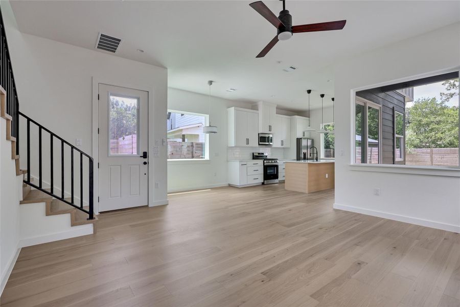 Clean lines and light-toned flooring define this open-concept living space with a modern kitchen and abundant natural illumination.