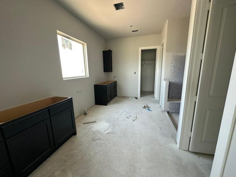 Interior space featuring newly installed dark cabinetry, a large window providing natural light, and a partially finished staircase