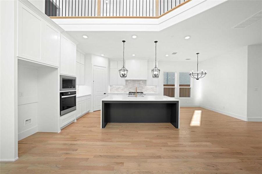 Kitchen with white cabinets, hanging light fixtures, oven, light wood-style flooring, and recessed lighting Kitchen with white cabinets, hanging light fixtures, oven, light wood-style flooring, and recessed lighting