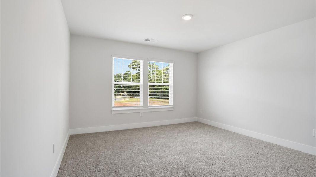 Highly functional bedroom with large windows, carpeted flooring, and tasteful finishes throughout