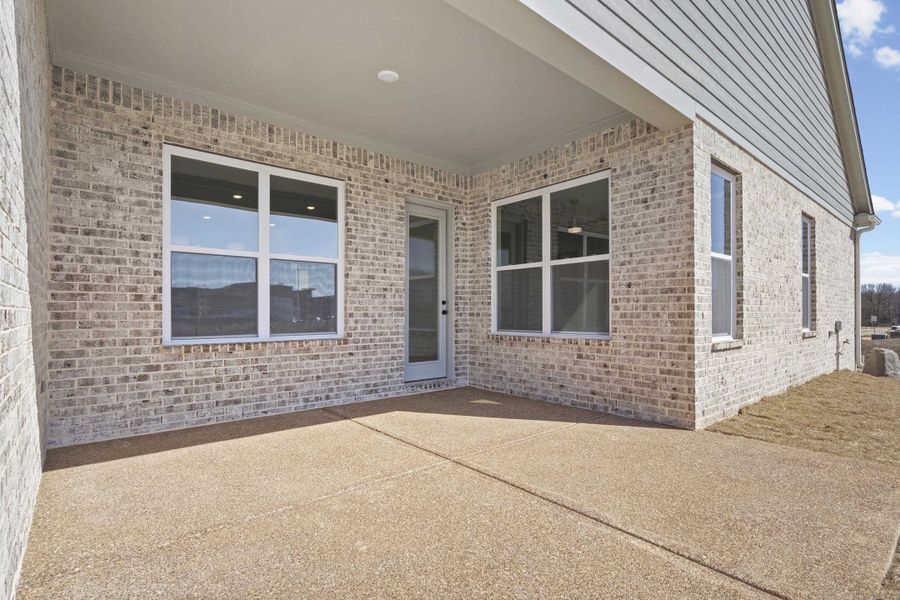 View of exterior entry featuring brick siding and a patio area