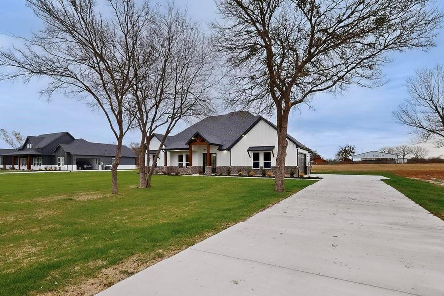 Modern inspired farmhouse with a front lawn and concrete driveway Modern inspired farmhouse with a front lawn and concrete driveway