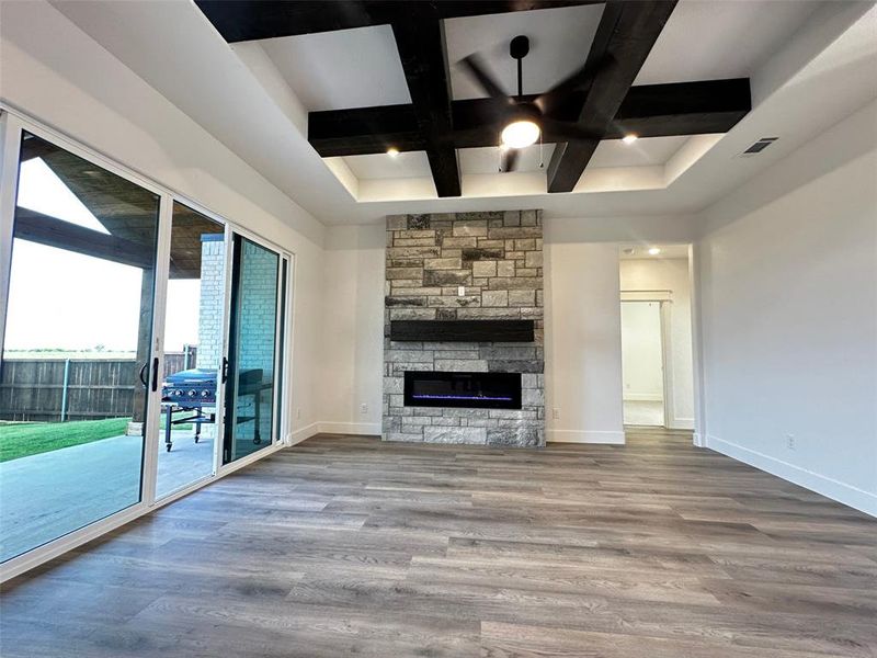 Unfurnished living room with coffered ceiling, wood finished floors, visible vents, baseboards, and ceiling fan