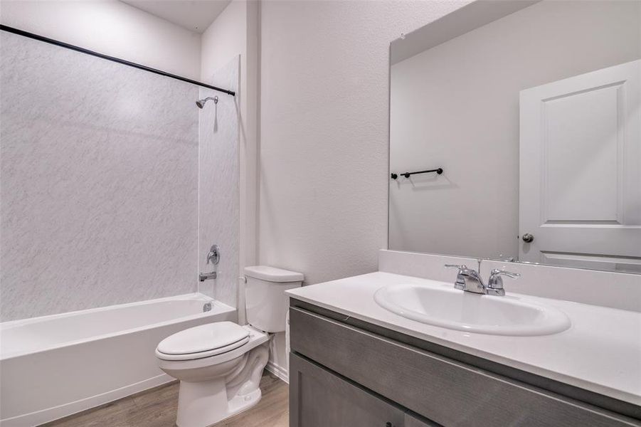Full bathroom with vanity, bathing tub / shower combination, and light wood finished floors Full bathroom with vanity, bathing tub / shower combination, and light wood finished floors