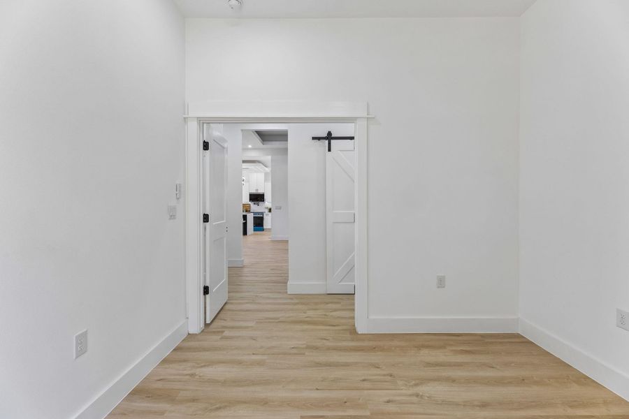 Smooth wood-look flooring and tall ceilings create a clean modern aesthetic throughout this space.