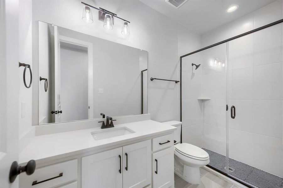 Bathroom featuring a single vanity with stone countertop, undermount sink, and black hardware