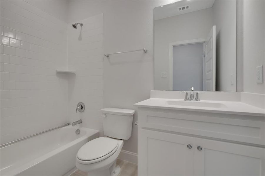 Full bathroom with vanity, tiled shower / bath combo, and toilet