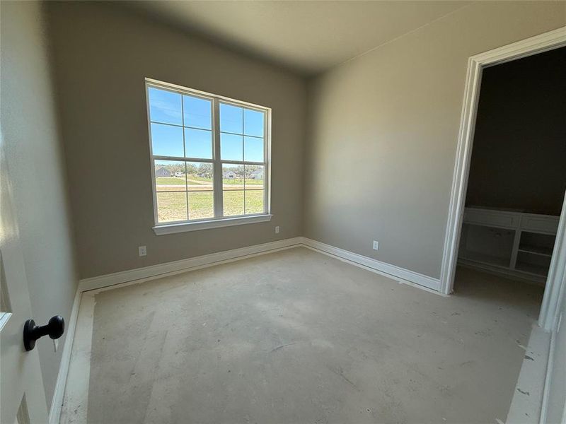 Unfurnished bedroom with unfinished concrete floors and baseboards