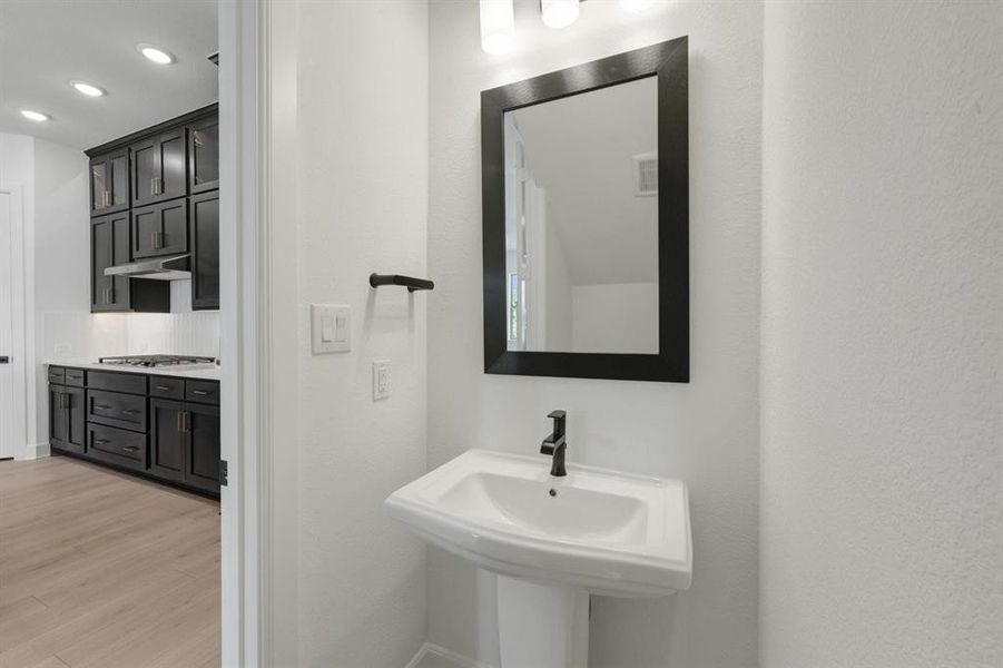 Pedestal sink with matte black faucet, framed mirror, and contemporary light fixture Pedestal sink with matte black faucet, framed mirror, and contemporary light fixture