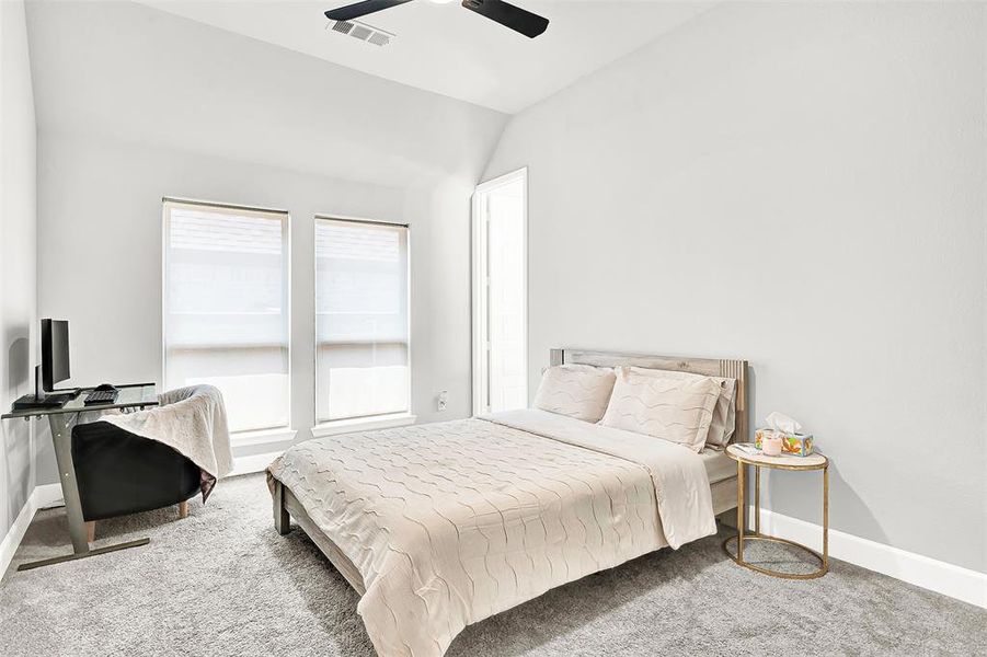 Carpeted bedroom with vaulted ceiling and ceiling fan