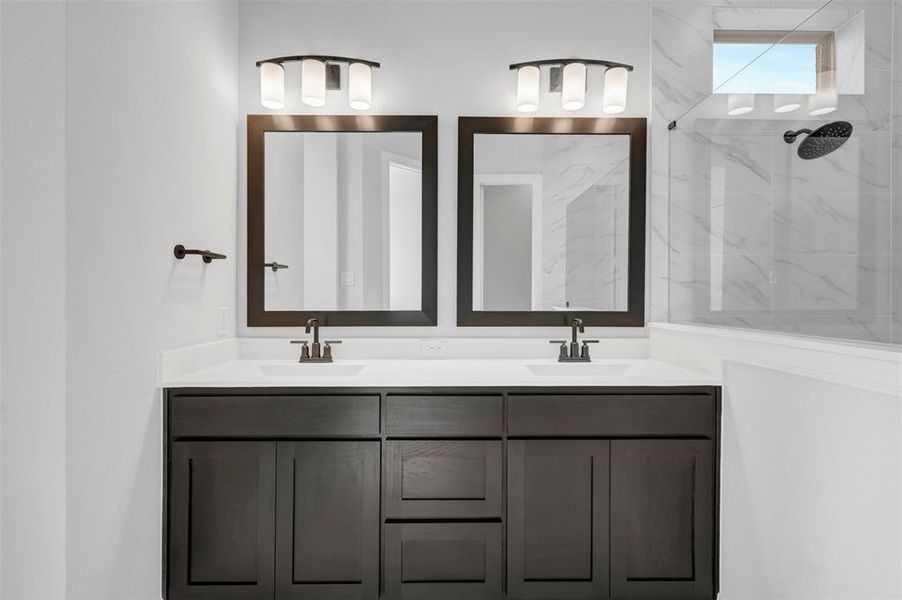 Bathroom featuring double vanity and a marble finish shower Bathroom featuring double vanity and a marble finish shower