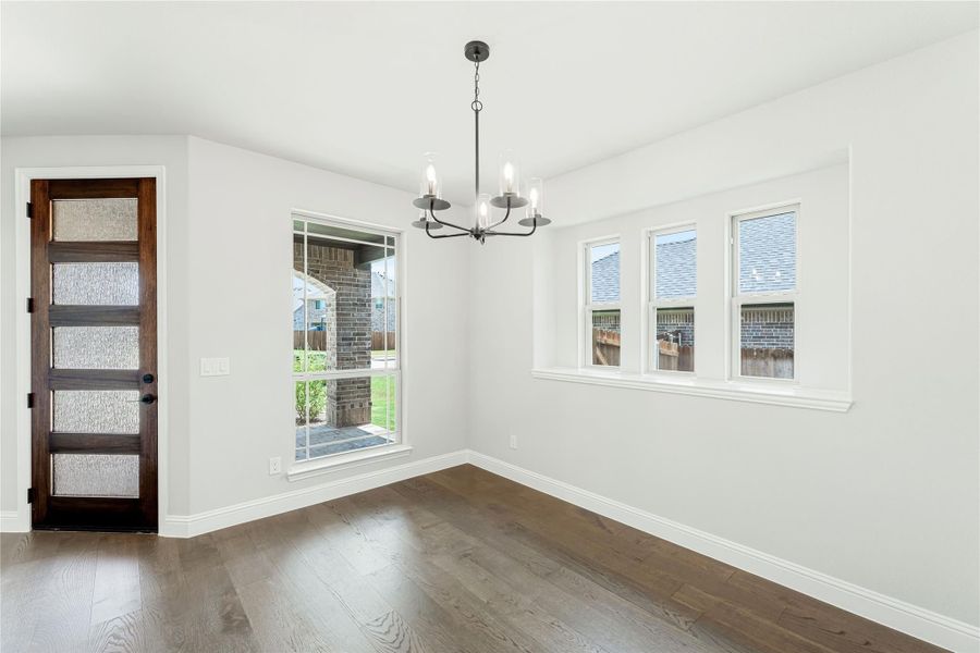 Empty dining room with dark hardwood floors, chandelier, and wood door with glass panels Empty dining room with dark hardwood floors, chandelier, and wood door with glass panels