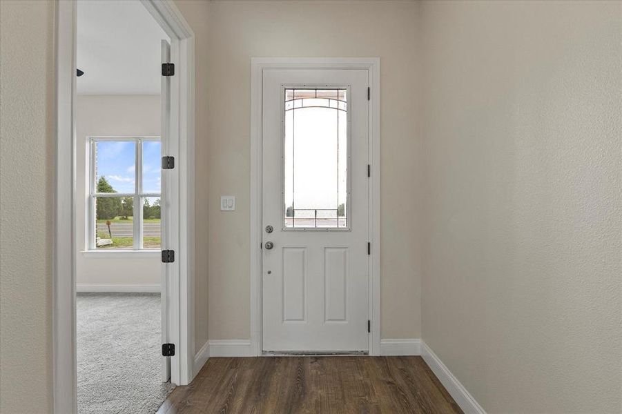 Doorway with baseboards and dark wood-style flooring